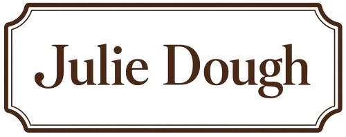 A white rectangular label with a brown border and the words 'Julie Dough' in brown serif text, centered on a white background.